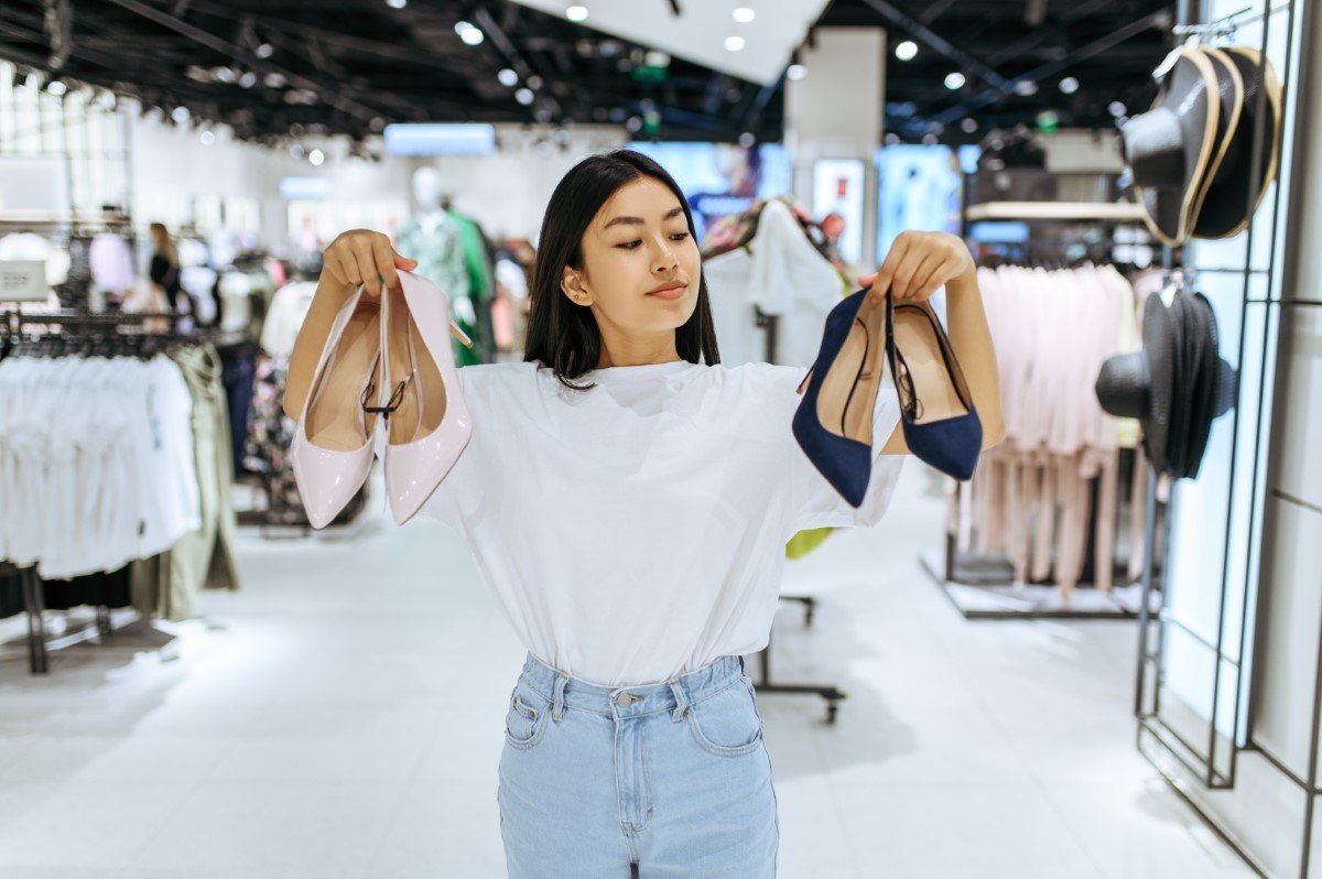 Cute woman choosing shoes in clothing store