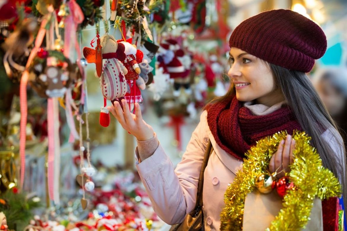 Girl choosing Christmas decoration at market.